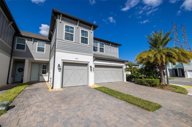 view of front of house featuring decorative driveway, an attached garage, board and batten siding, and stucco siding