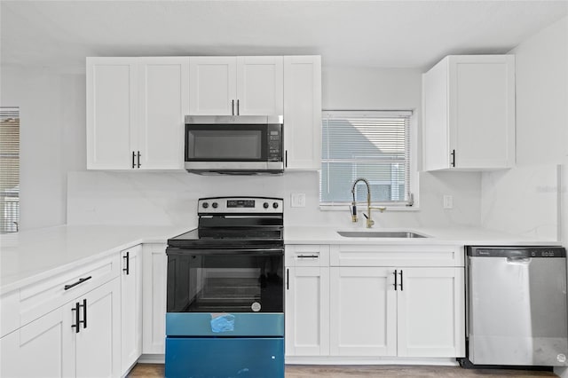 kitchen with white cabinets, sink, decorative backsplash, light wood-type flooring, and stainless steel appliances