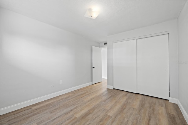 unfurnished bedroom featuring light hardwood / wood-style floors and a closet