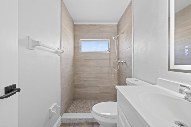 bathroom featuring tiled shower, vanity, and toilet