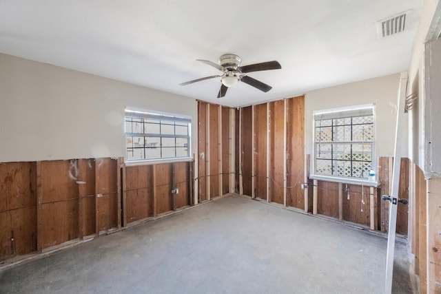 empty room featuring a wealth of natural light, ceiling fan, and concrete floors