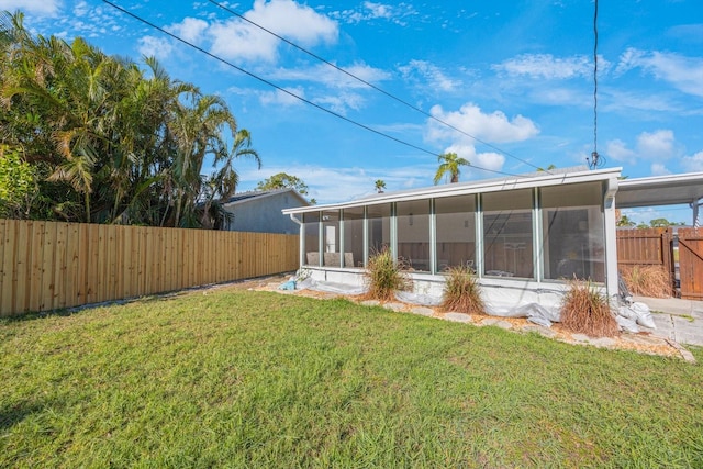 rear view of property featuring a sunroom and a yard