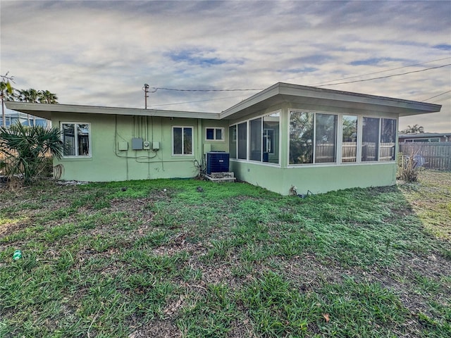 back of house featuring a sunroom, a lawn, and central air condition unit