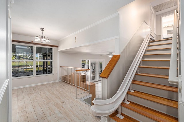 stairway featuring hardwood / wood-style flooring, ceiling fan with notable chandelier, and ornamental molding