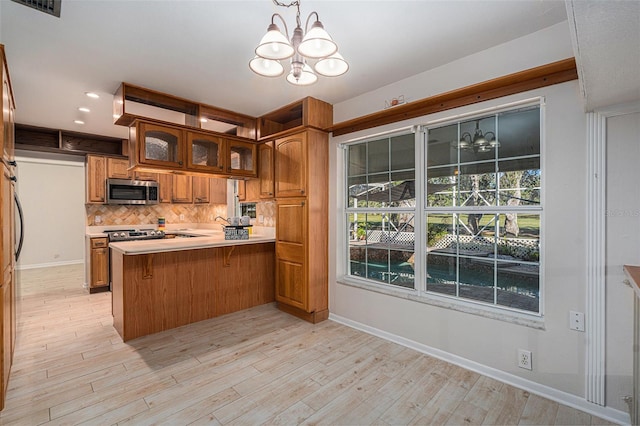 kitchen with an inviting chandelier, backsplash, kitchen peninsula, pendant lighting, and a breakfast bar area