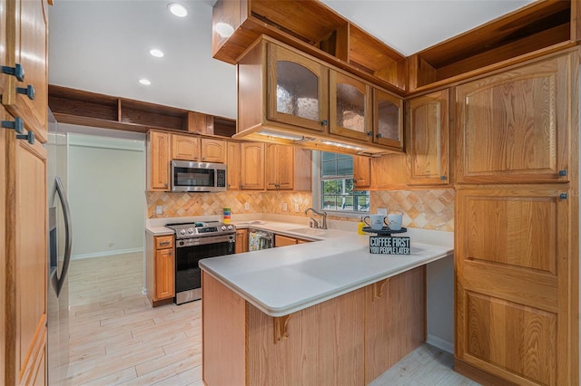 kitchen featuring kitchen peninsula, sink, stainless steel appliances, and light hardwood / wood-style floors