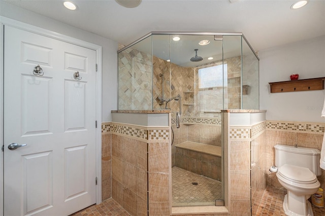 bathroom with tile patterned flooring, a tile shower, toilet, and tile walls