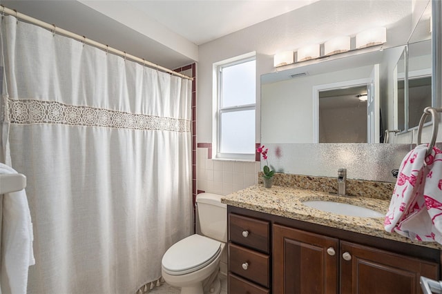 bathroom with vanity, toilet, and tile walls