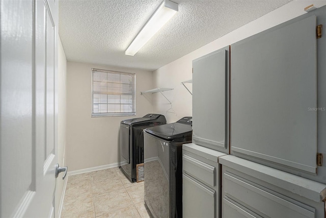 clothes washing area featuring separate washer and dryer, light tile patterned flooring, cabinets, and a textured ceiling