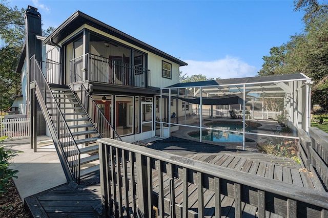 rear view of property with a patio, a fenced in pool, glass enclosure, and a balcony