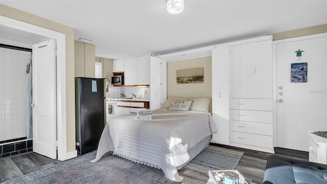 bedroom with black fridge and dark wood-type flooring