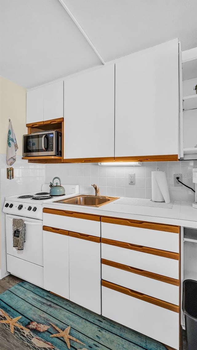 kitchen featuring decorative backsplash, sink, wood-type flooring, range, and white cabinetry