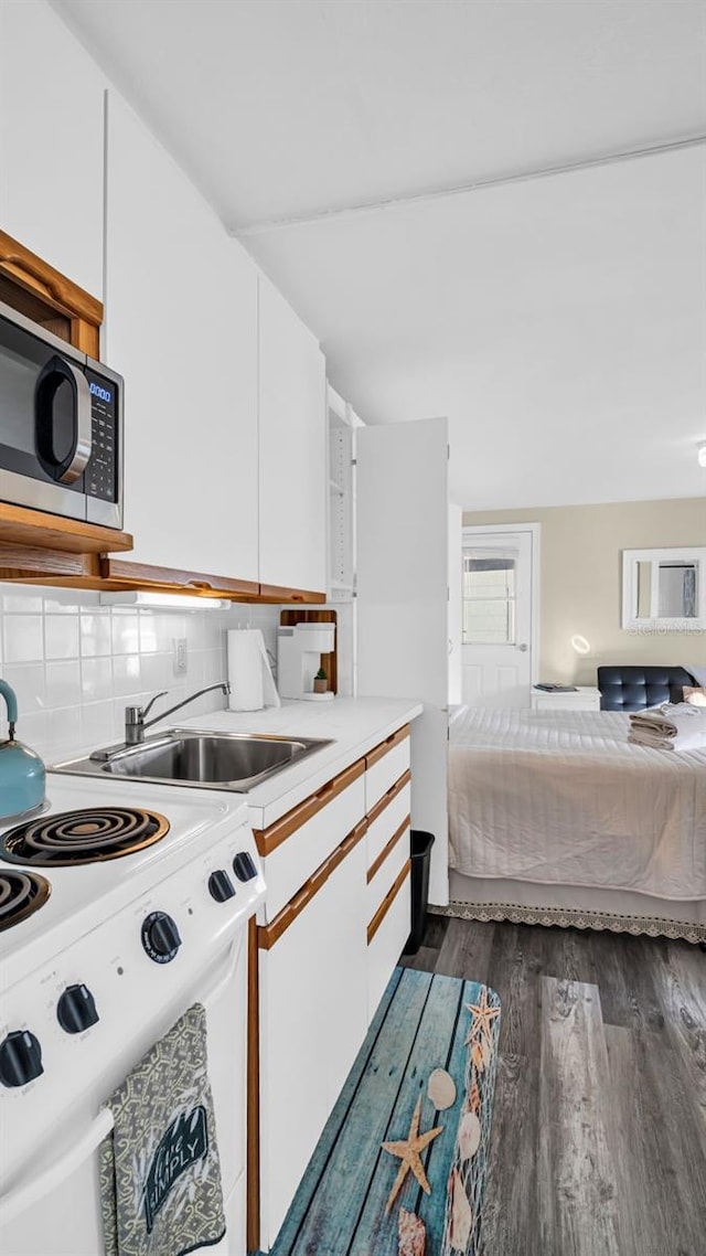 kitchen featuring electric range, dark hardwood / wood-style floors, white cabinetry, and sink