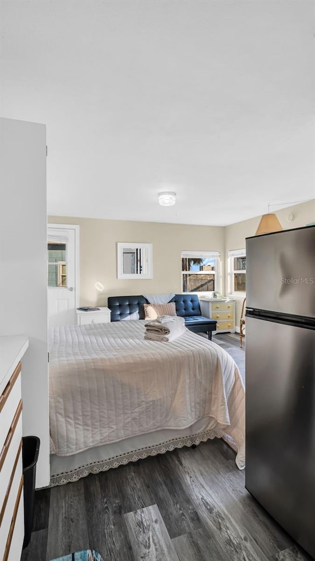 bedroom with stainless steel fridge, hardwood / wood-style flooring, and multiple windows