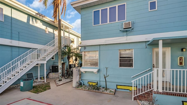 back of property featuring a wall unit AC, a patio area, water heater, and central AC unit