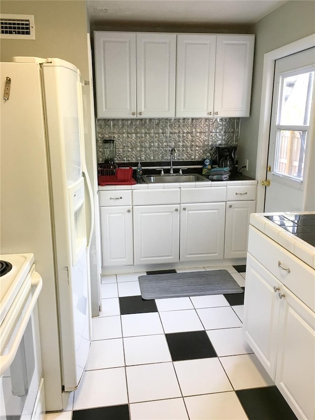 kitchen featuring tile countertops, white cabinetry, sink, and tasteful backsplash