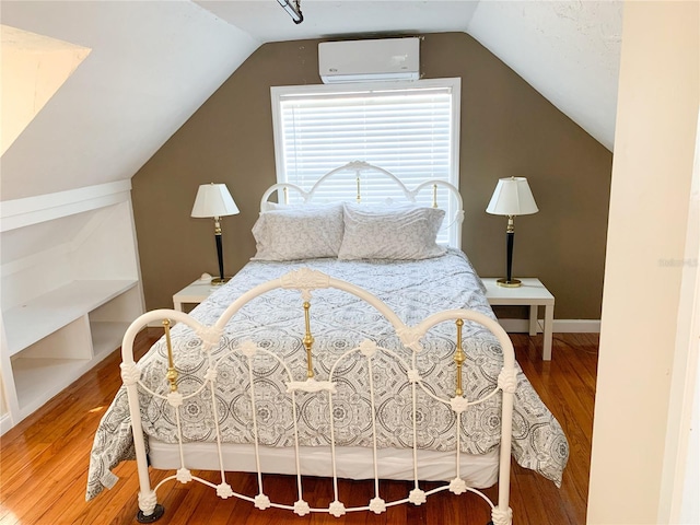 bedroom with wood-type flooring, a wall mounted AC, and vaulted ceiling