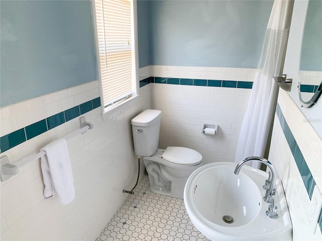 bathroom with tile patterned floors, toilet, and tile walls