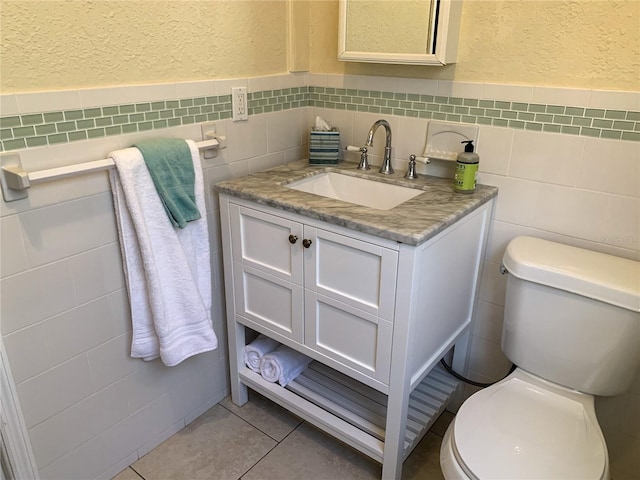 bathroom with tile patterned floors, vanity, tile walls, and toilet