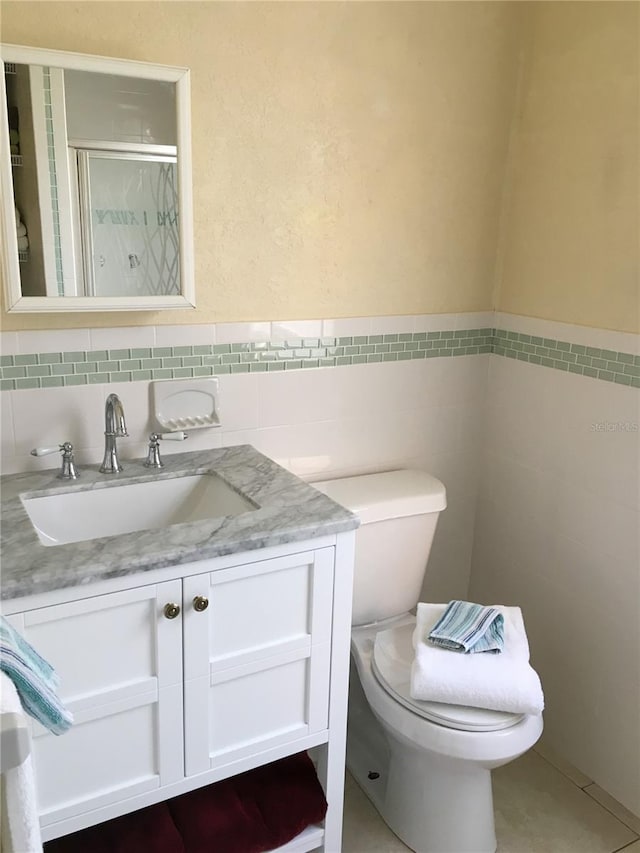 bathroom featuring toilet, vanity, tile walls, and walk in shower