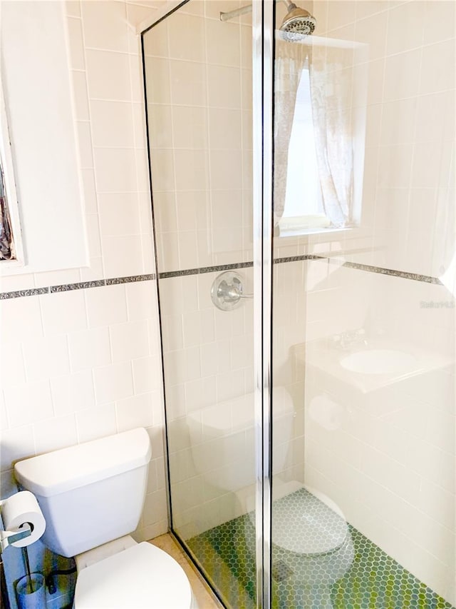 bathroom with a shower with shower door, tile walls, and toilet