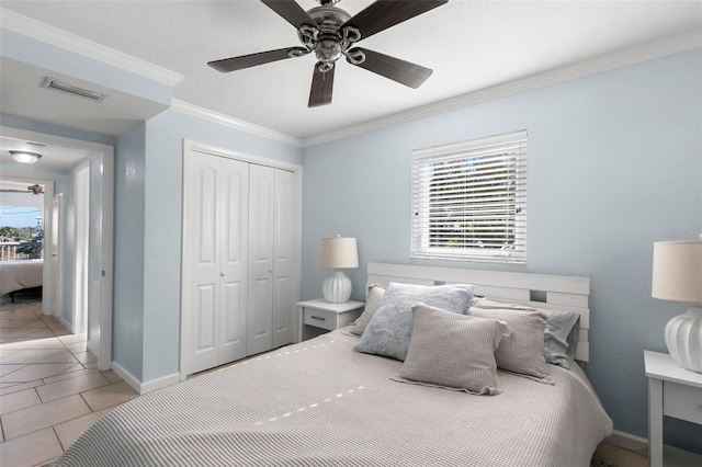 bedroom featuring ceiling fan, light tile patterned floors, a closet, and ornamental molding