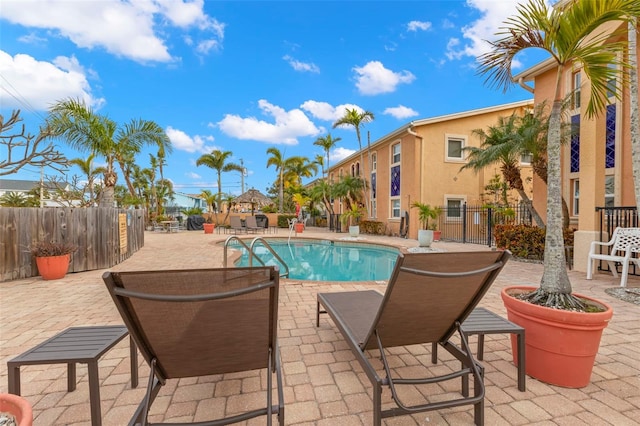 community pool with a patio and fence