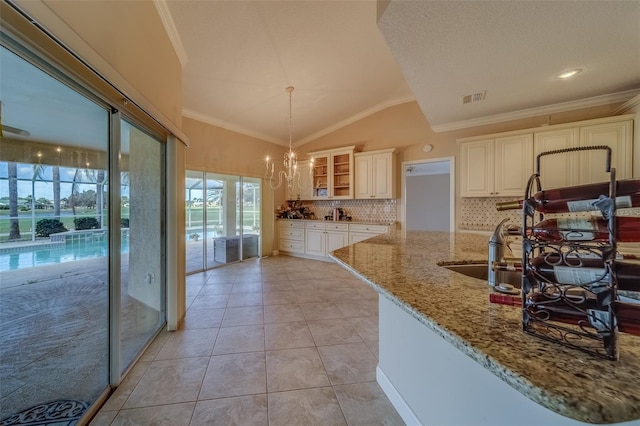 kitchen featuring vaulted ceiling, light stone counters, crown molding, and sink