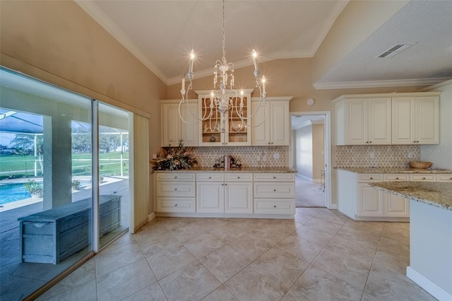 kitchen with backsplash, crown molding, decorative light fixtures, and lofted ceiling