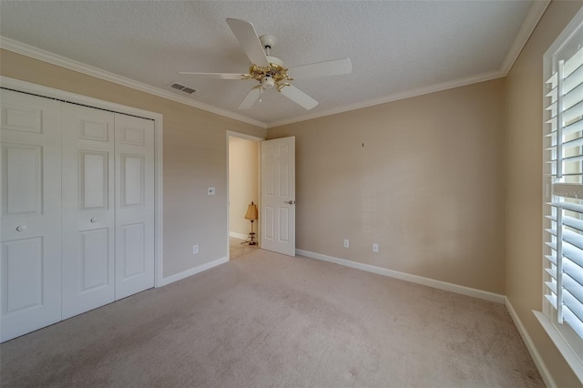 unfurnished bedroom featuring light carpet, a closet, ceiling fan, and crown molding