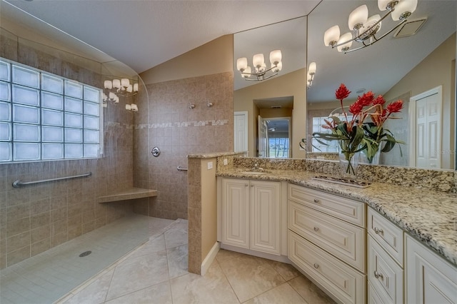 bathroom featuring vanity, lofted ceiling, tile patterned flooring, tiled shower, and a notable chandelier