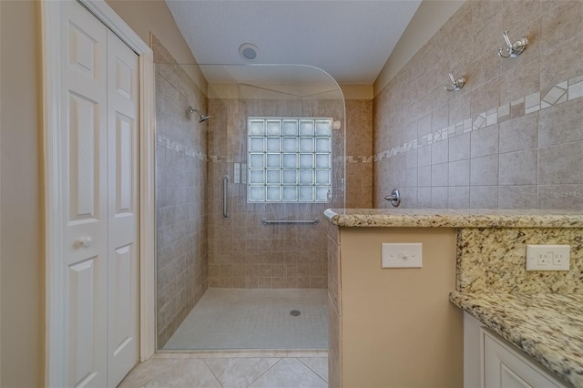 bathroom featuring tile patterned flooring, a tile shower, and tile walls