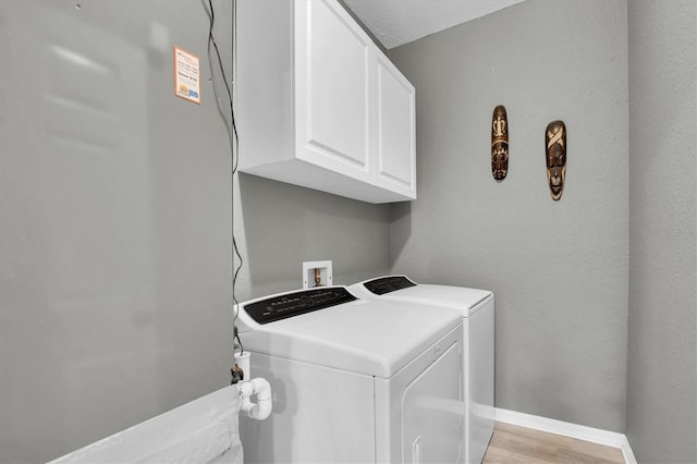 laundry area featuring cabinets, separate washer and dryer, and light hardwood / wood-style floors