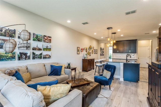 living room with light hardwood / wood-style floors and sink