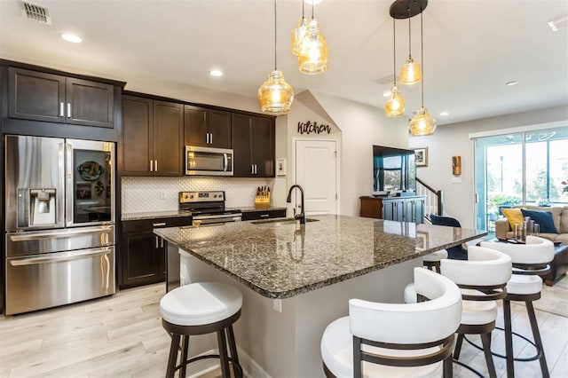 kitchen featuring sink, decorative light fixtures, dark brown cabinets, appliances with stainless steel finishes, and light wood-type flooring