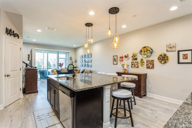 kitchen featuring pendant lighting, light hardwood / wood-style floors, stainless steel dishwasher, and sink