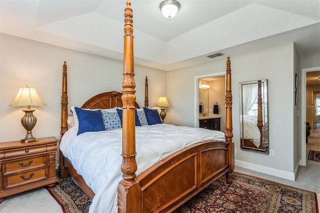 carpeted bedroom with ensuite bath, lofted ceiling, and a tray ceiling