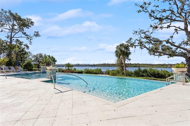 view of swimming pool featuring pool water feature, a water view, and a patio