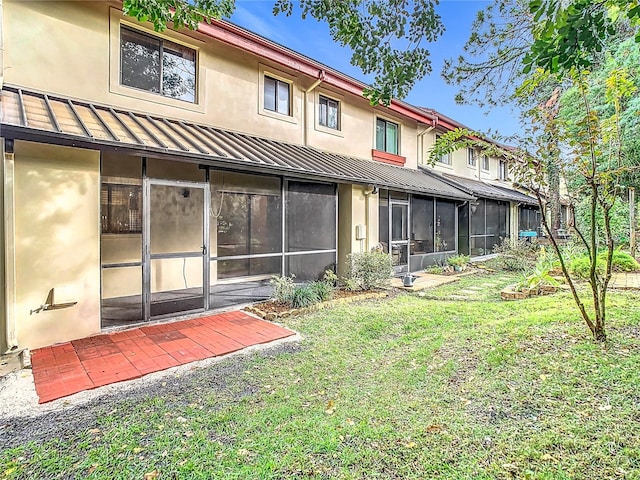 rear view of house featuring a yard and a sunroom