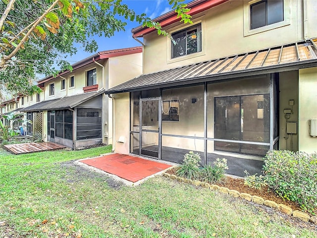 rear view of house featuring a lawn and a sunroom