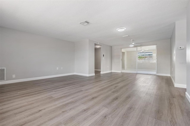 empty room featuring ceiling fan, a textured ceiling, and light hardwood / wood-style flooring