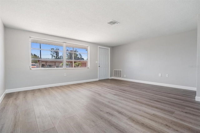 unfurnished room with a textured ceiling and light hardwood / wood-style floors