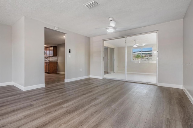 spare room with ceiling fan, wood-type flooring, and a textured ceiling