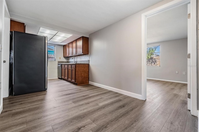 kitchen featuring tasteful backsplash, refrigerator, and light wood-type flooring