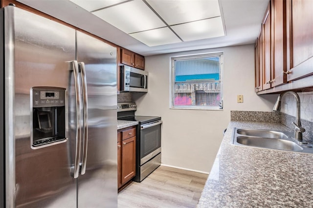 kitchen with decorative backsplash, sink, light hardwood / wood-style flooring, and appliances with stainless steel finishes