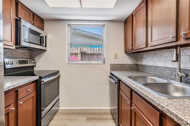 kitchen featuring appliances with stainless steel finishes, backsplash, light hardwood / wood-style flooring, and sink