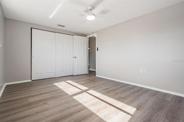 unfurnished bedroom featuring wood-type flooring, a closet, and ceiling fan