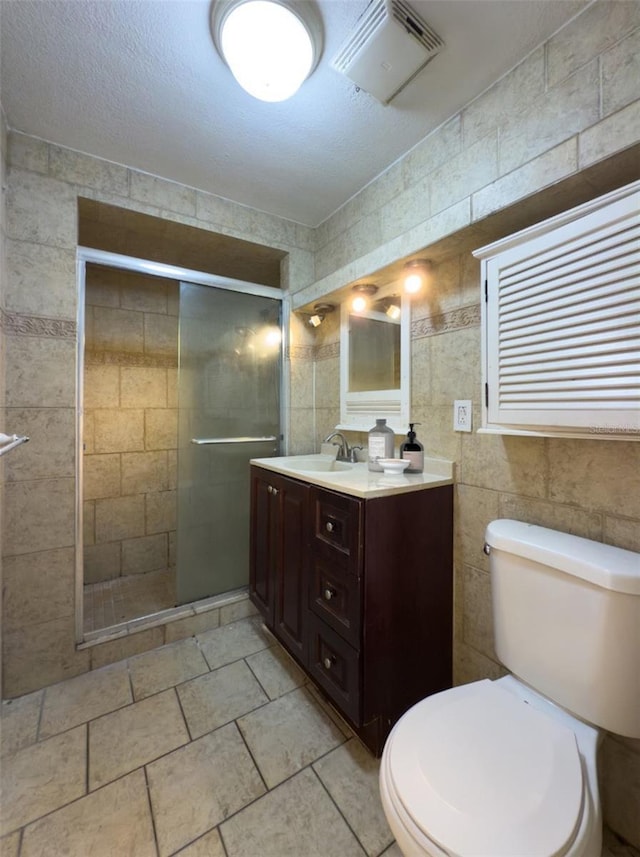 bathroom with toilet, a shower with door, tile walls, a textured ceiling, and vanity