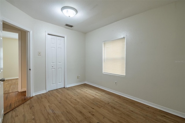 unfurnished bedroom with a closet and wood-type flooring