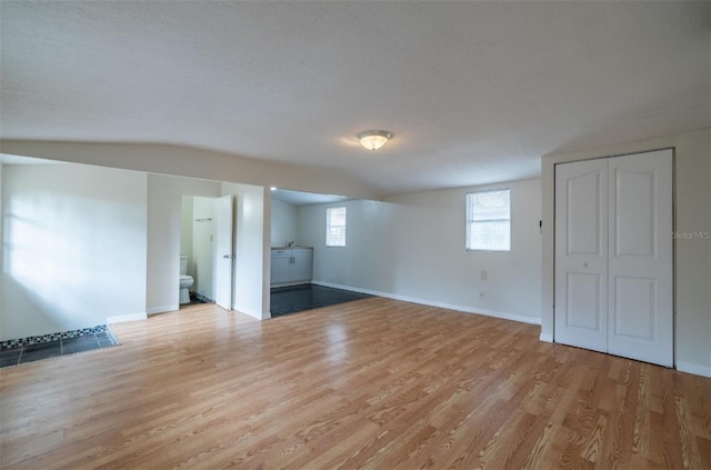 unfurnished room featuring light wood-type flooring and lofted ceiling